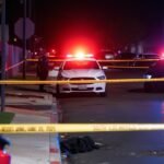 Police tape surrounds a South Los Angeles street at night, with emergency lights illuminating a crime scene where a fatal shooting and carjacking occurred.