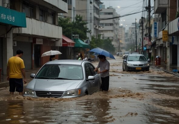 A flooded street in Busan, South Korea, with water covering roads and vehicles partially submerged, as people navigate through the deluge under gray skies.